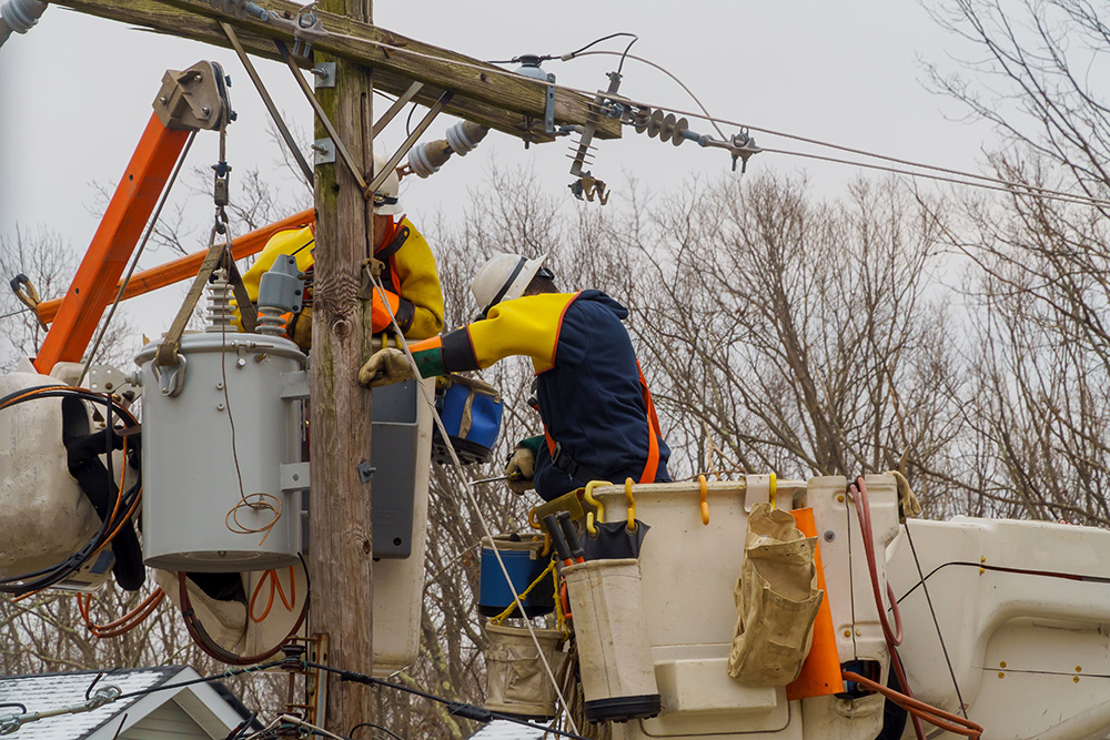 Utility workers repairing electrical wiring on poles